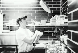Smiling pizzaiolo tossing dough in a warm, inviting kitchen.