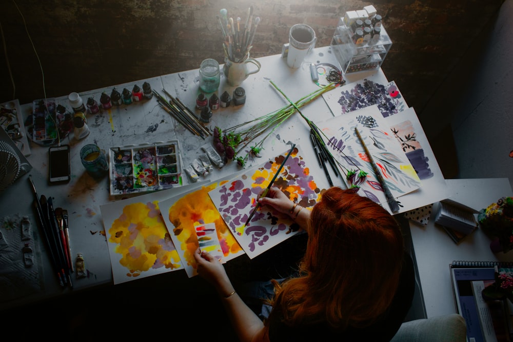 woman sitting in front on table while painting