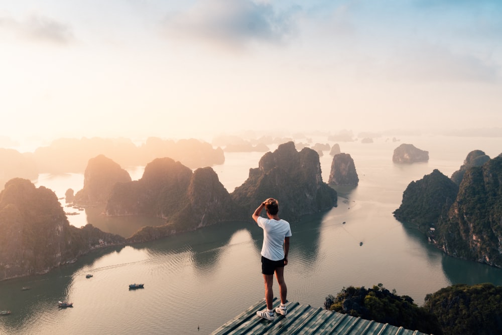 man standing on hill overlooking islands