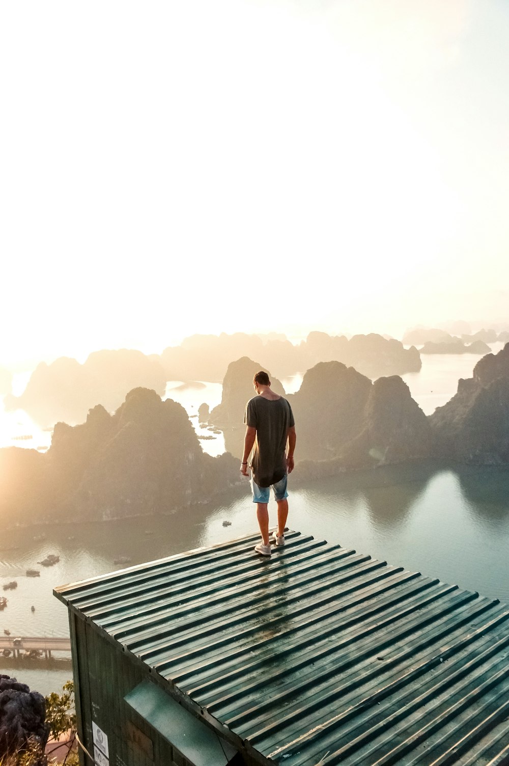 man standing on roof near body of water during golden hour