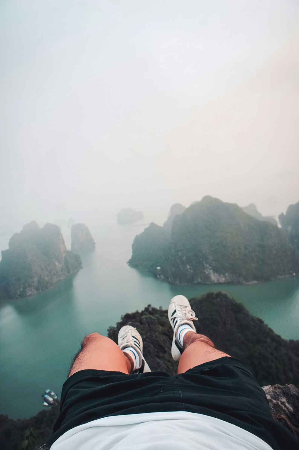 a person laying on top of a mountain next to a body of water