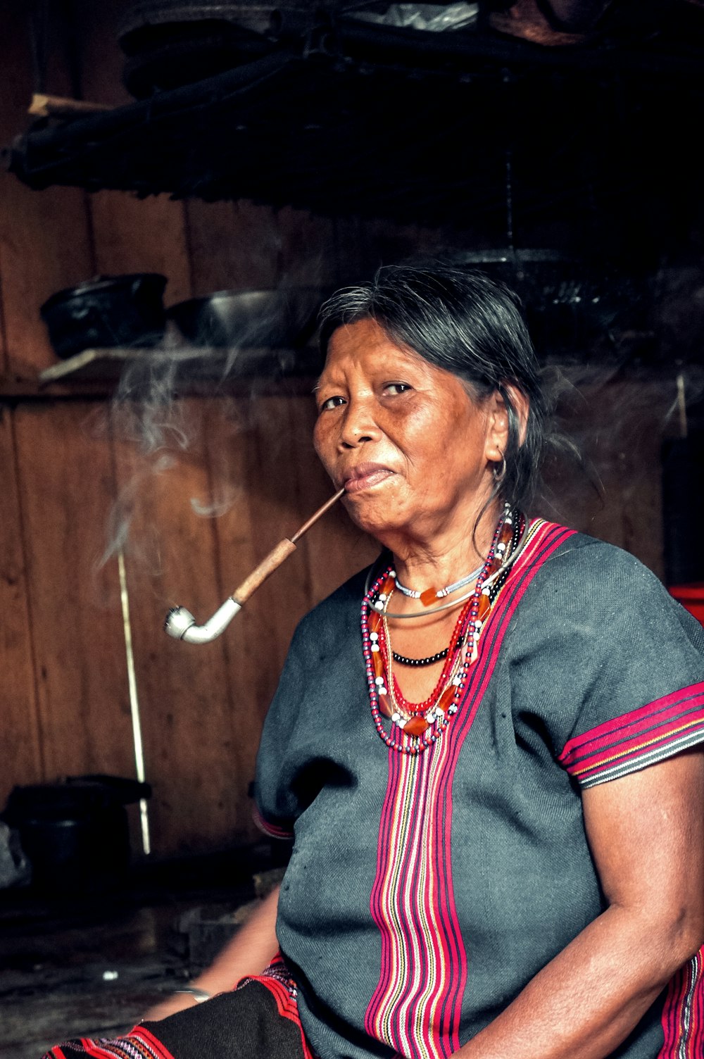 woman smoking while sitting near brown wall