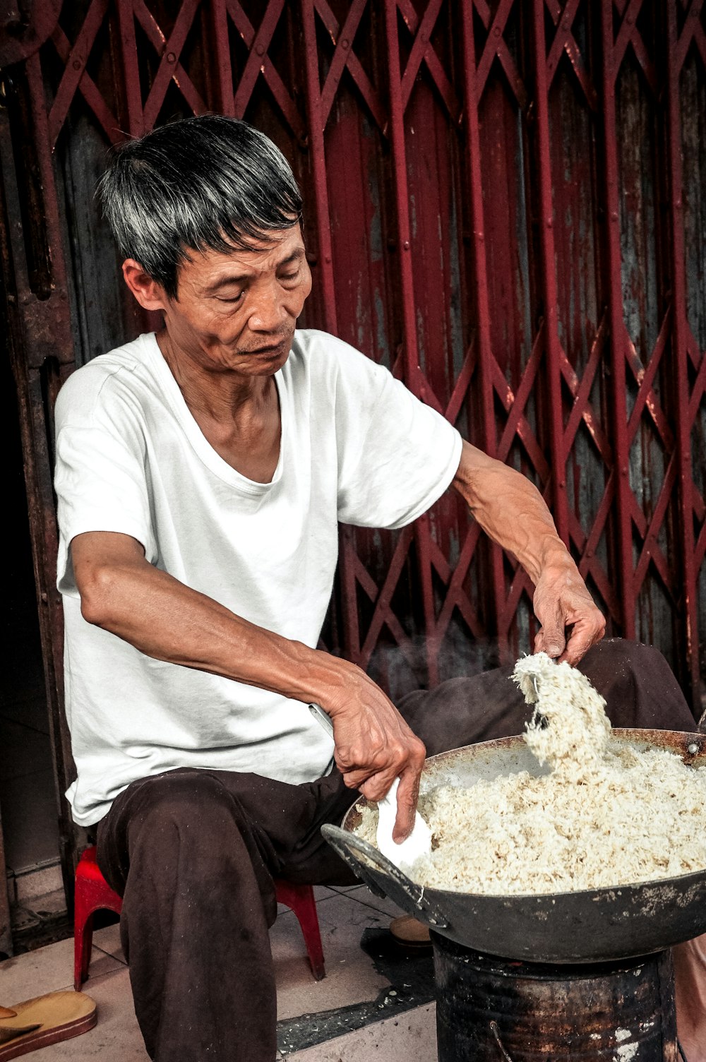 man in white crew-neck t-shirt cooking in wok