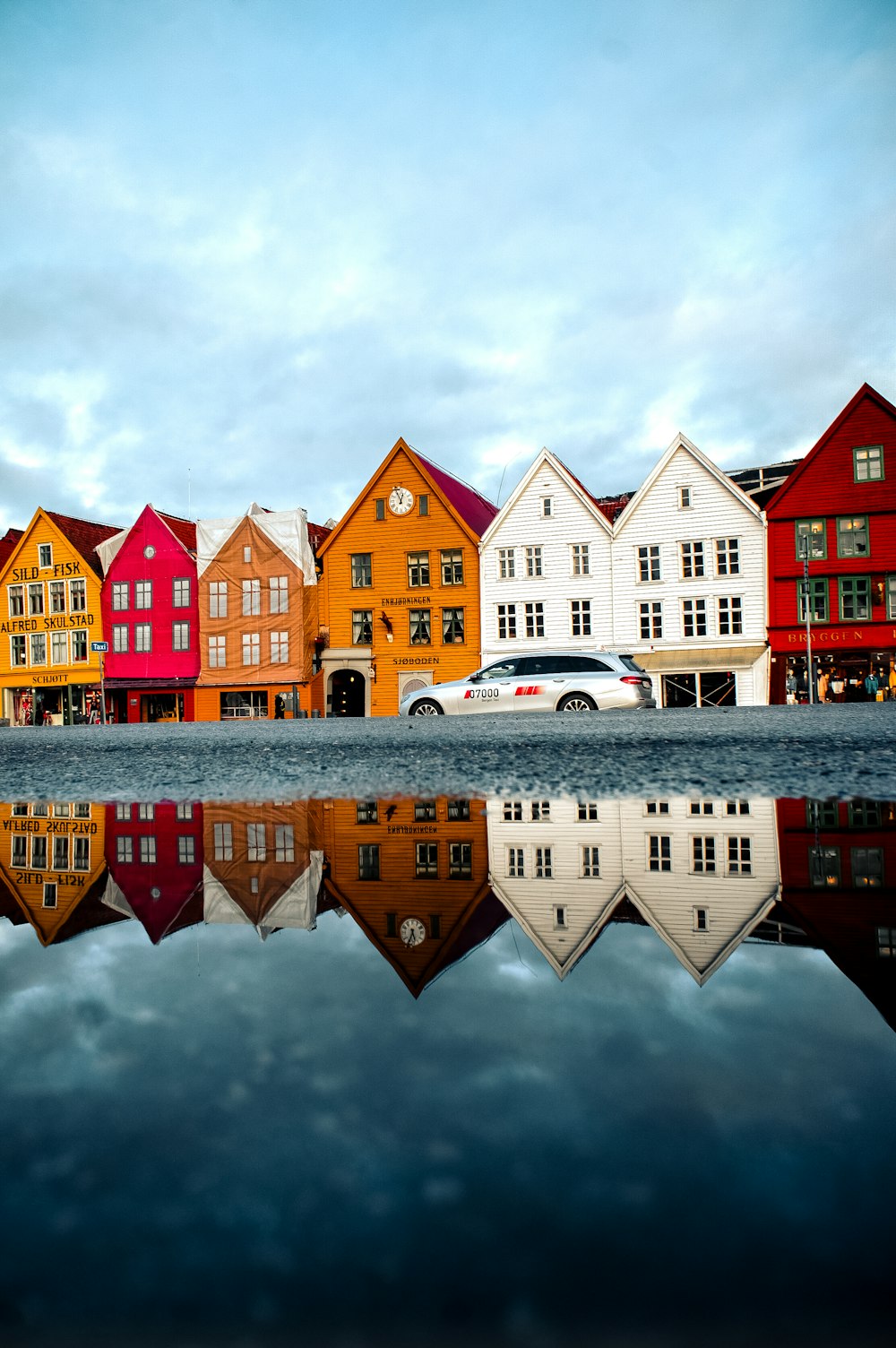 silver vehicle park near multicolored houses during daytime