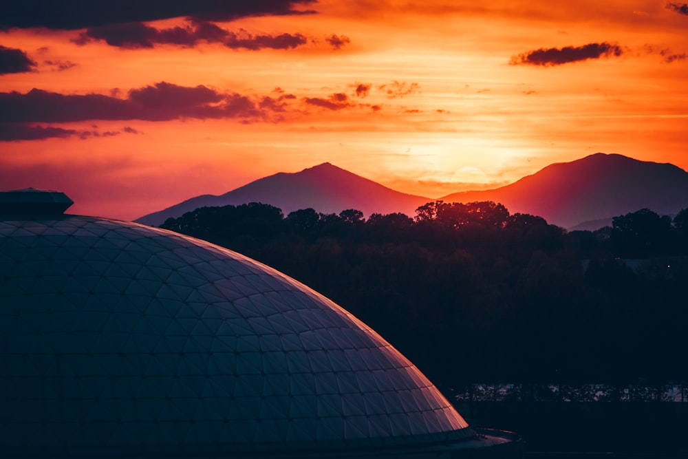 building near trees and mountains at the distance during golden hour