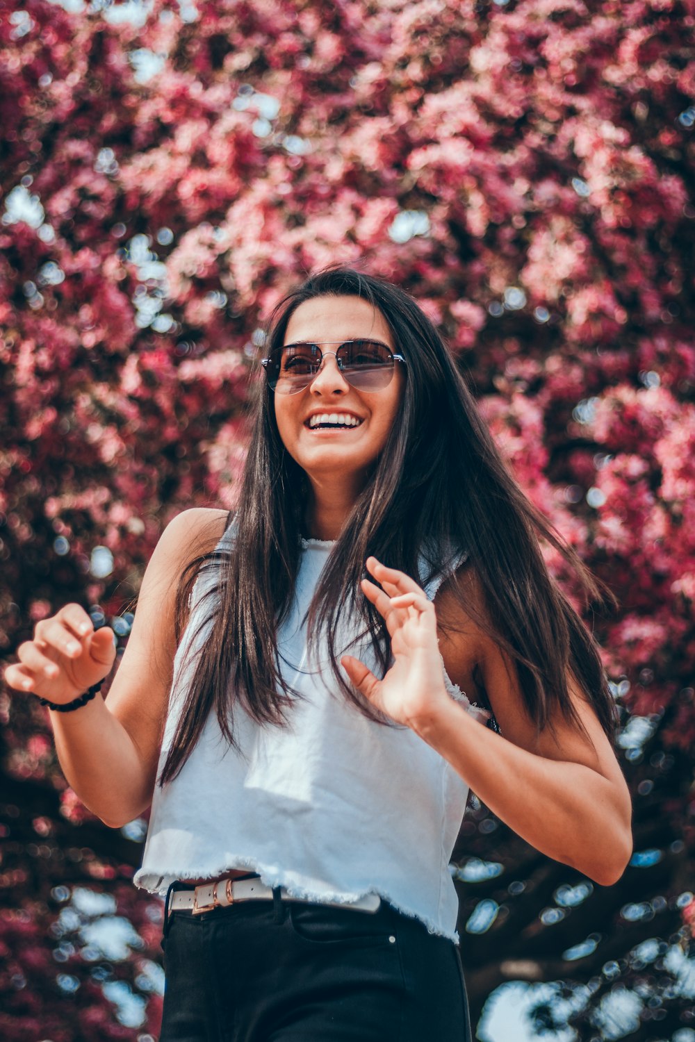 smiling woman standing in front of pink flowers