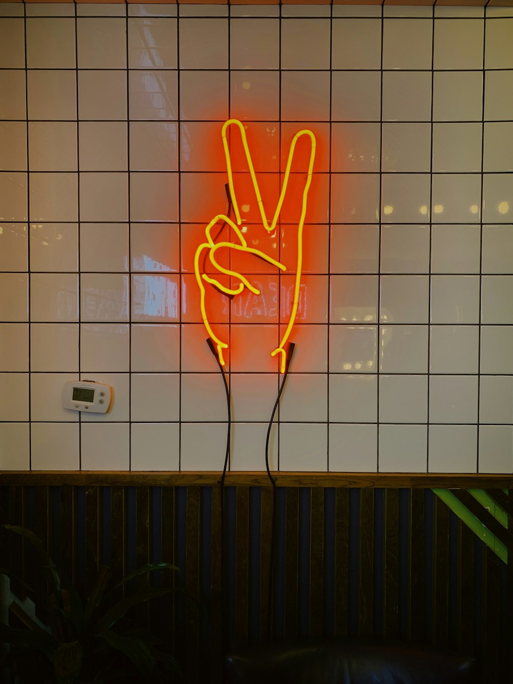 orange LED peace sign on tiled wall
