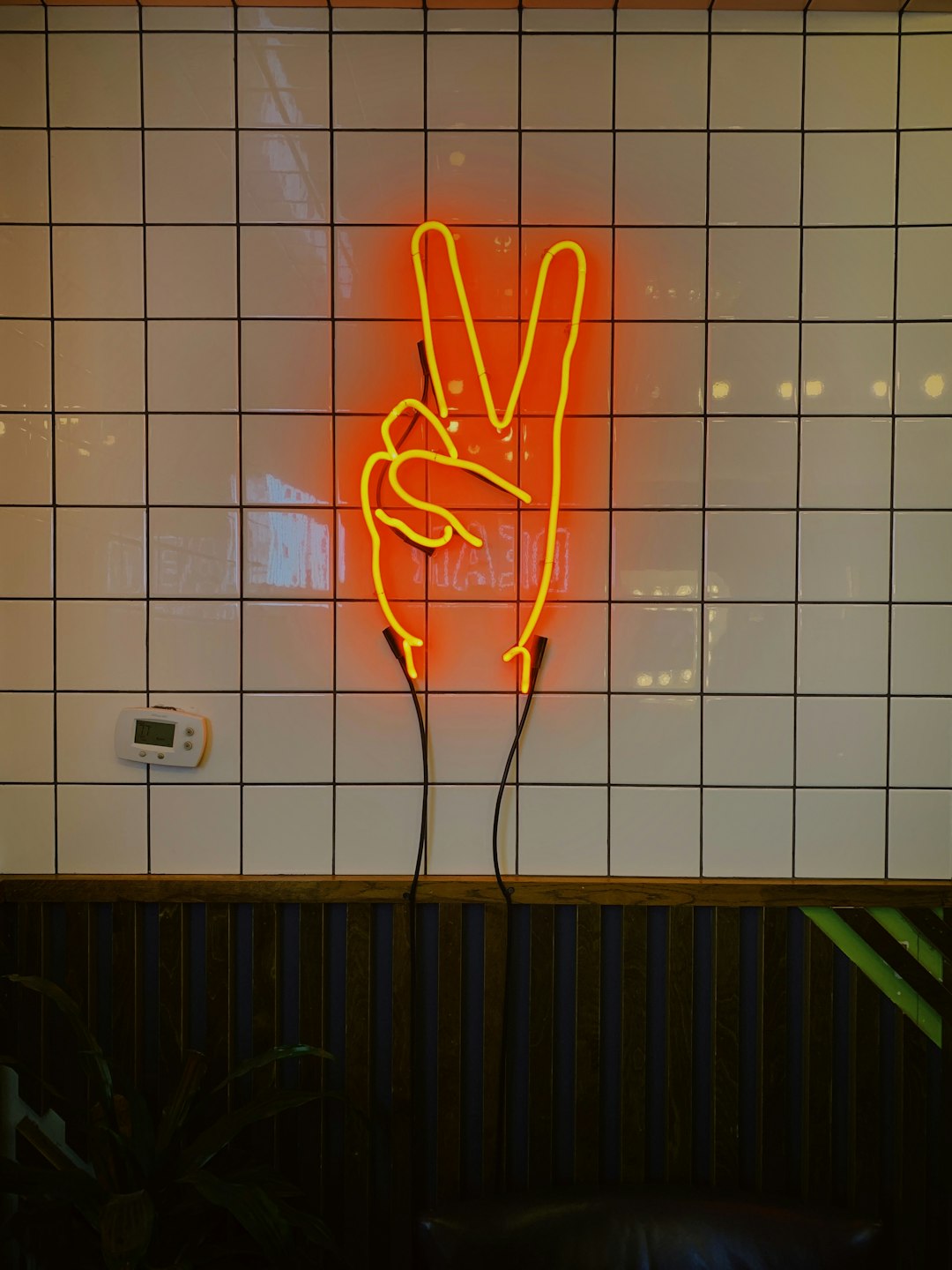 orange LED peace sign on tiled wall