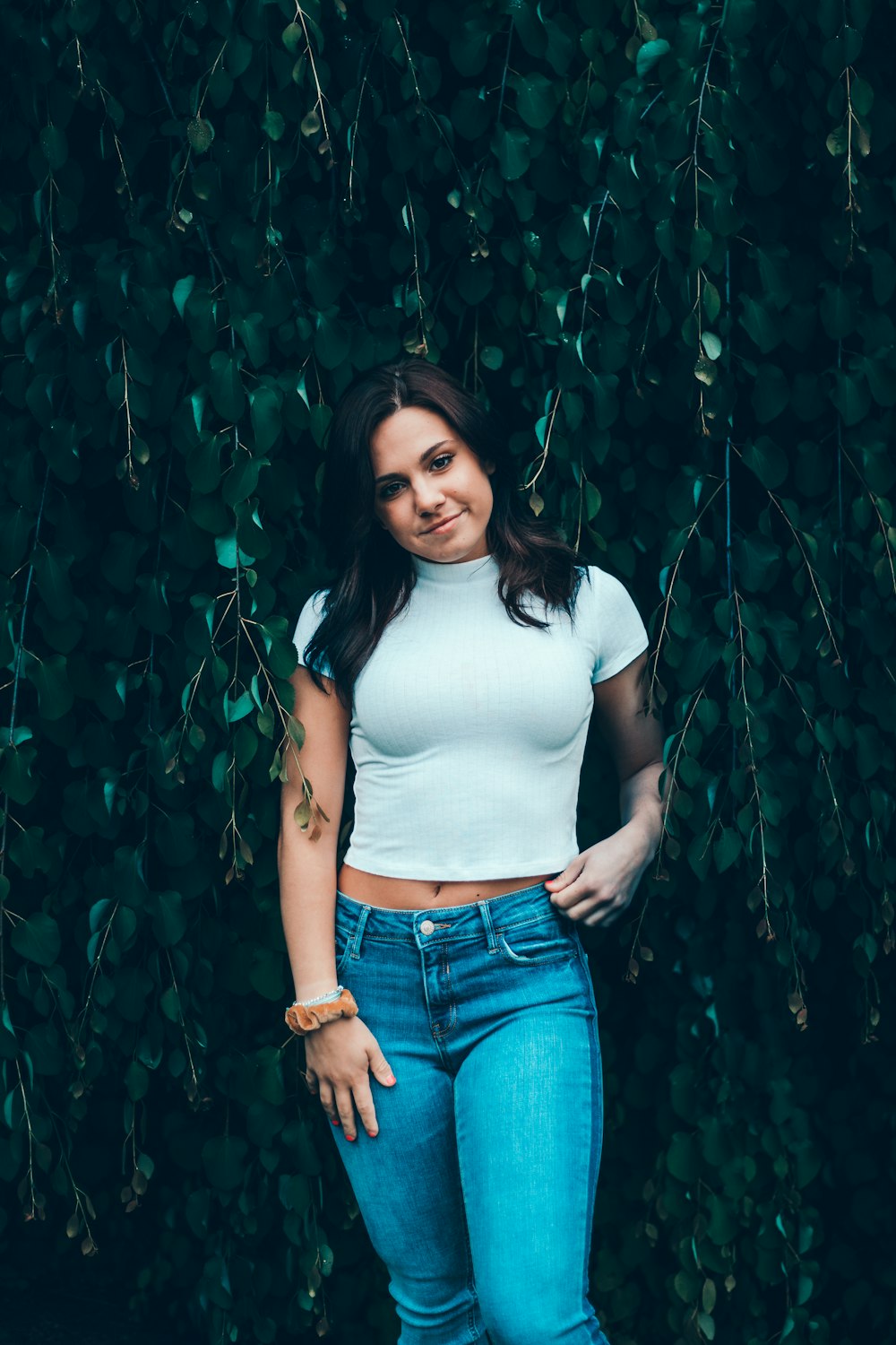 smirking woman standing beside green leaves