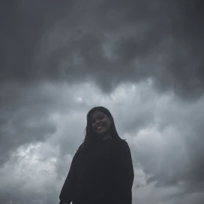 A dramatic movie poster featuring a hero standing against a stormy sky backdrop