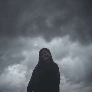 A dramatic movie poster featuring a hero standing against a stormy sky backdrop