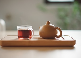 clear glass cup with tea near brown ceramic teapot