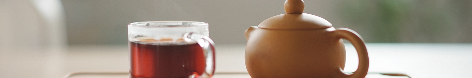 clear glass cup with tea near brown ceramic teapot