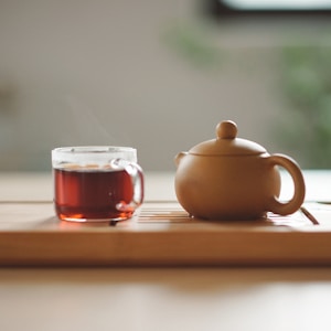 clear glass cup with tea near brown ceramic teapot