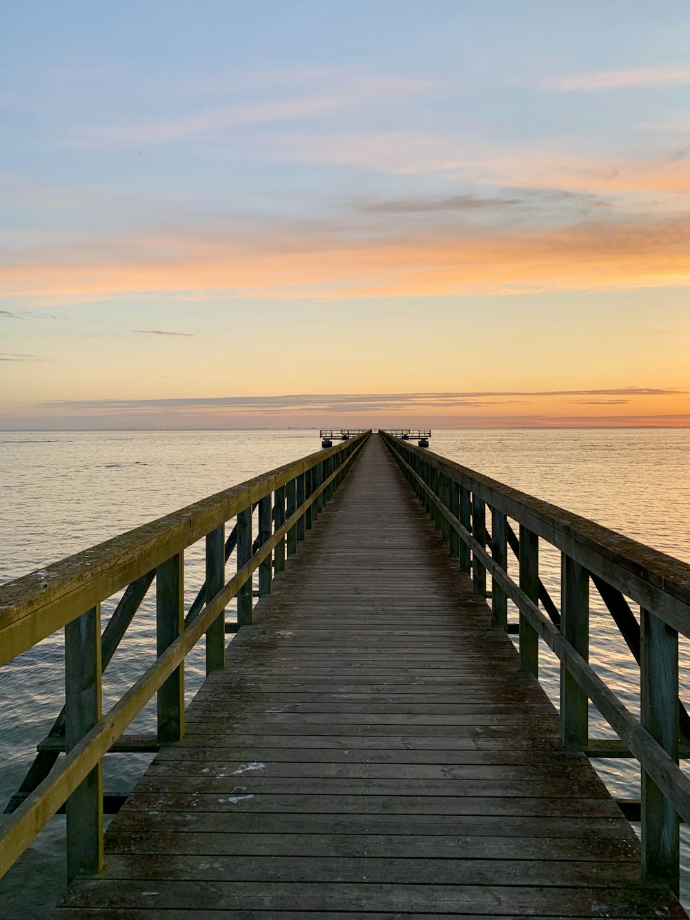 brown wooden dock under gray clouds during golden hour