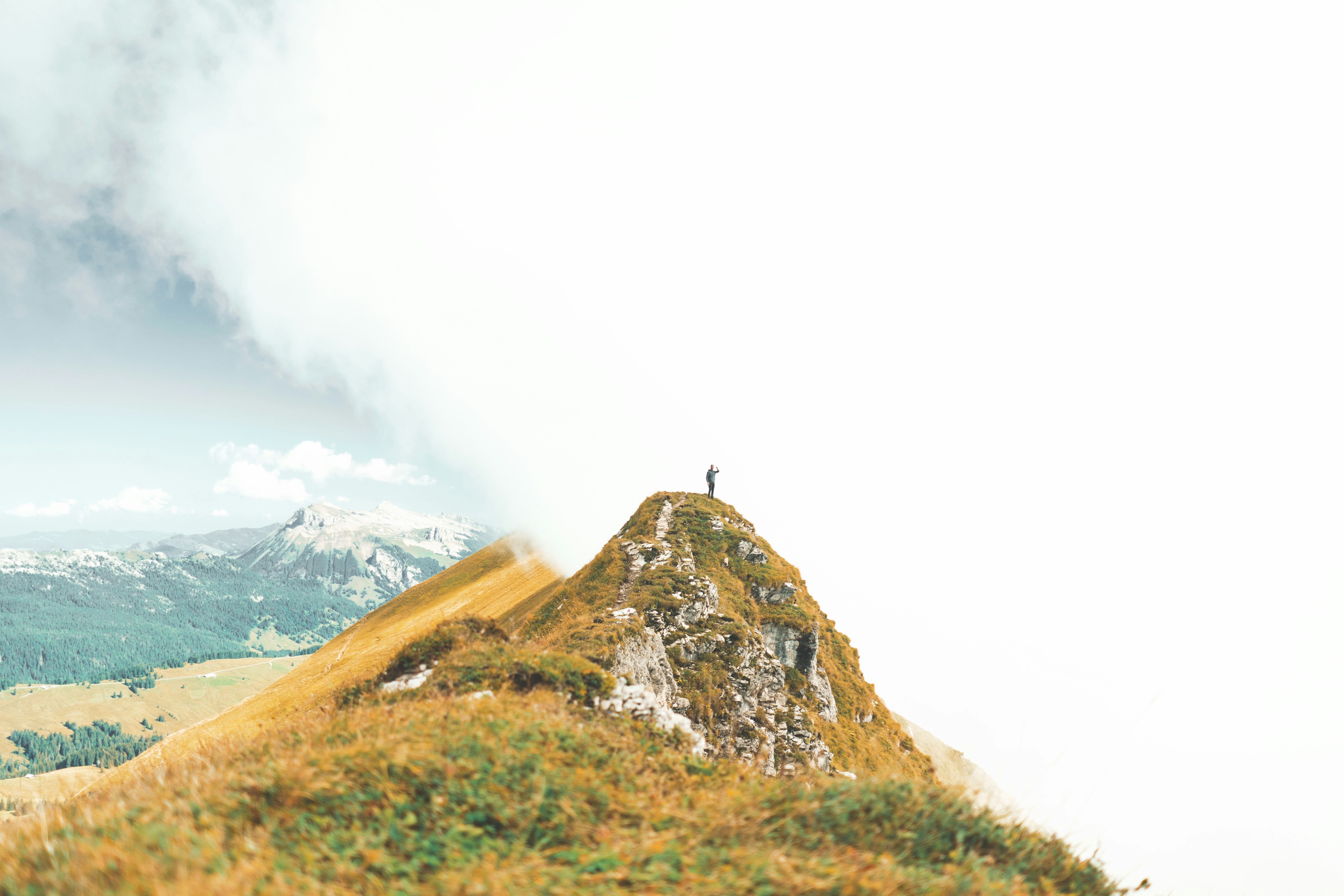 A person silhouetted on a mountaintop at sunrise, looking victorious.
