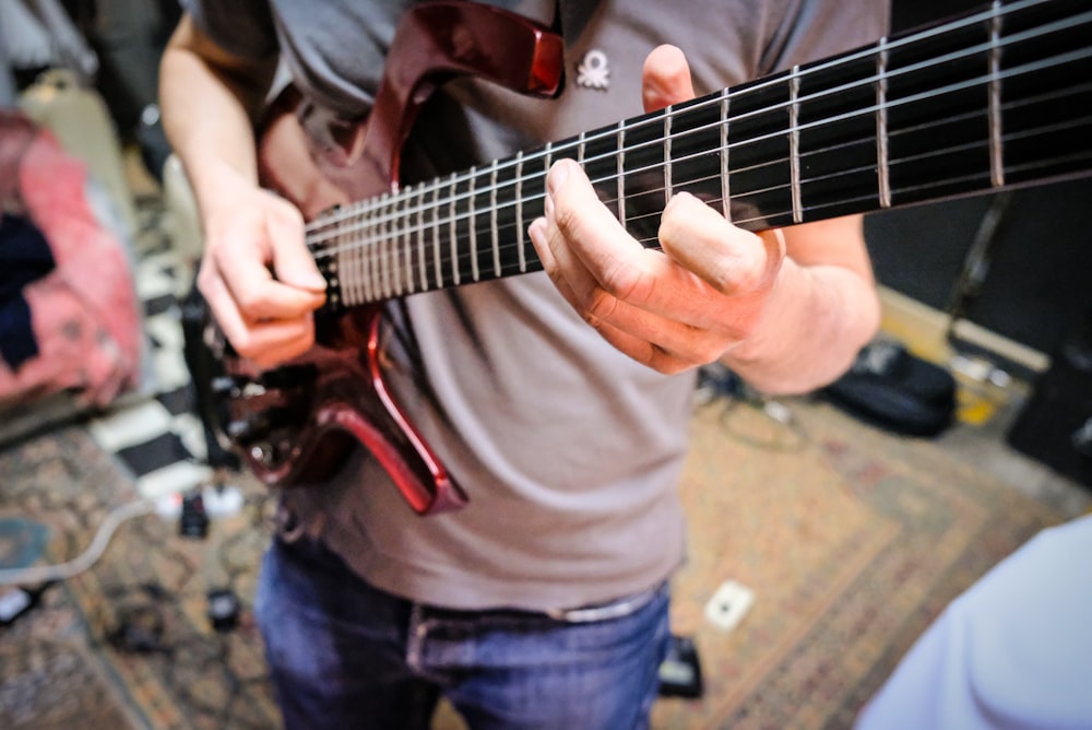 uomo in camicia grigia che suona la chitarra