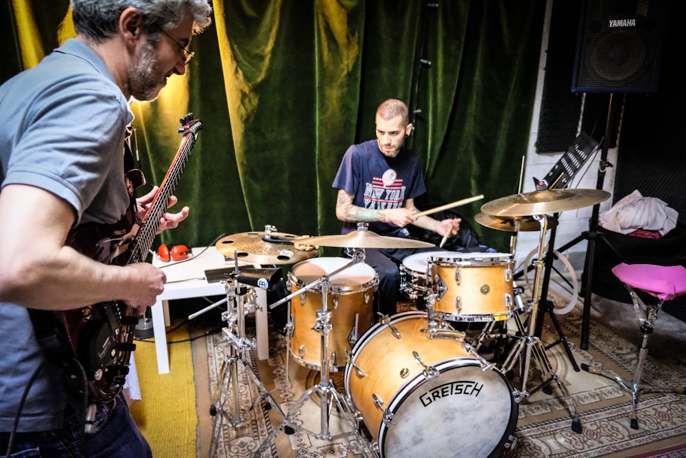 man in blue t-shirt playing drum set