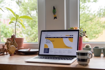 laptop on desk. There's greenery outside the window