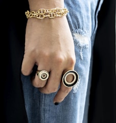 Close-up of hands accessorizing with chunky rings and vintage scarves.