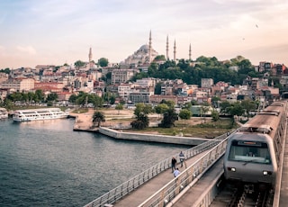 gray and black train traveling on top of bridge during daytime