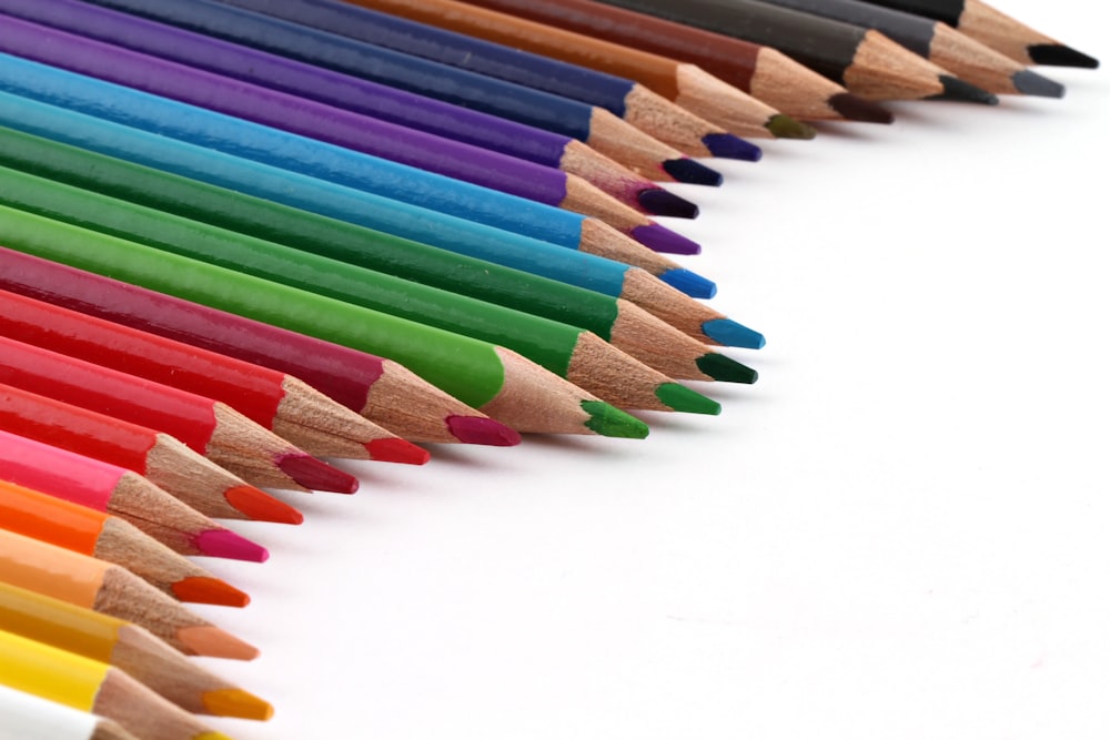 Lápices de colores de todos los colores sobre panel blanco