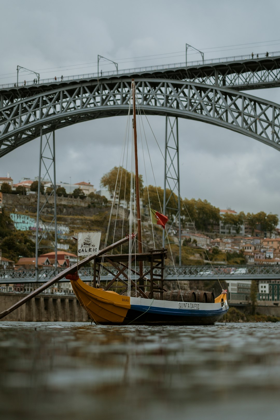 white and yellow sailboat traveling passed by bridge during daytime