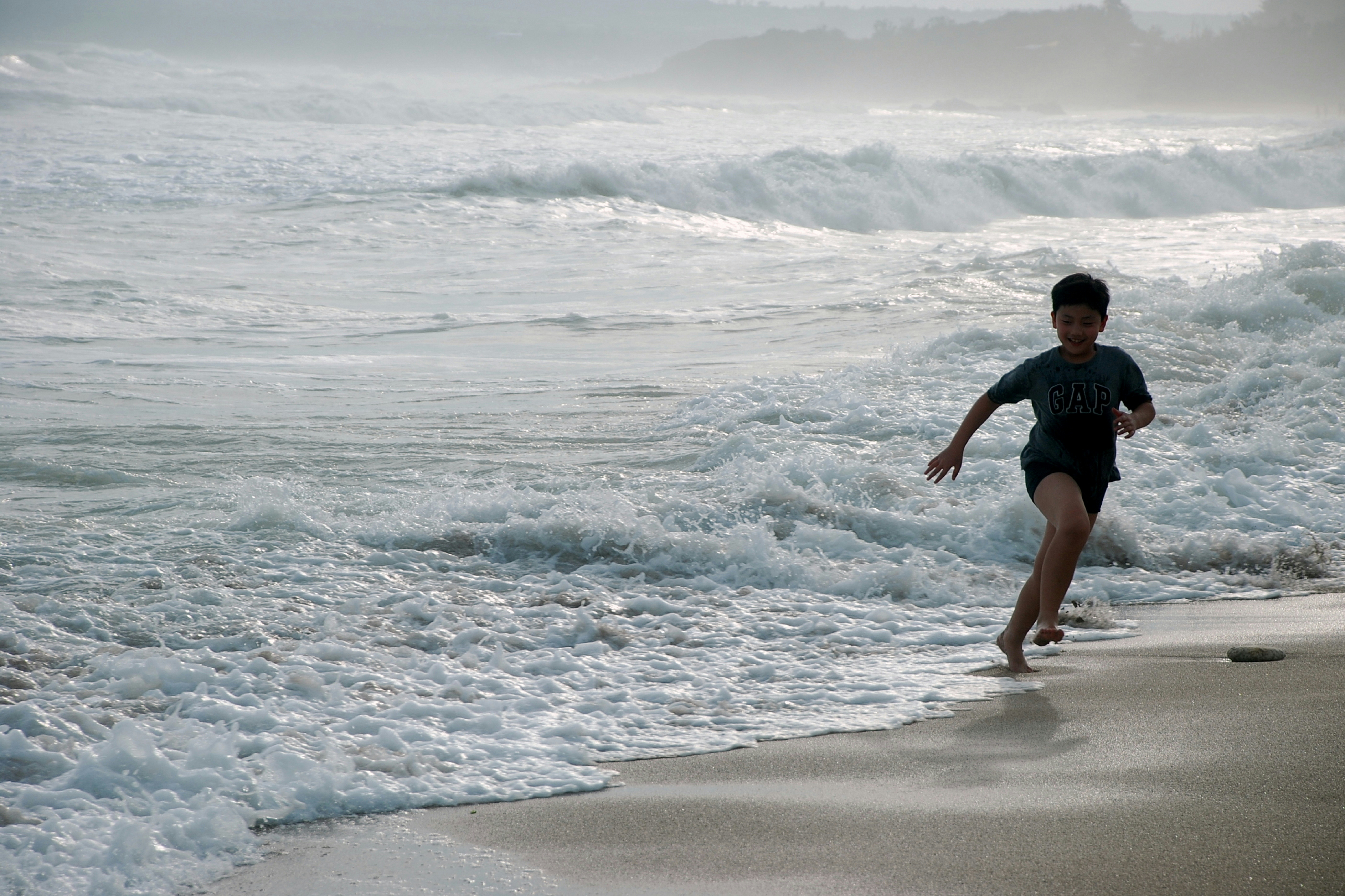 menino correndo na praia durante o dia