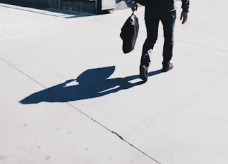A person carrying grocery bags while walking down a sunny street.
