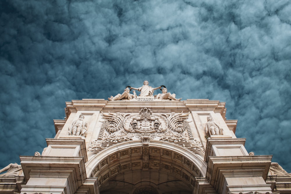 white concrete arch under cloudy sky