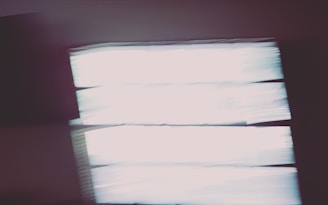 Blurry image with rectangular shapes resembling windows or light panels. The bright areas contrast with dark surroundings, creating an abstract effect.