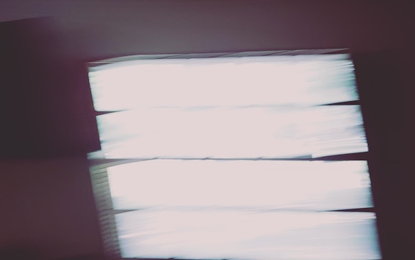 Blurry image with rectangular shapes resembling windows or light panels. The bright areas contrast with dark surroundings, creating an abstract effect.