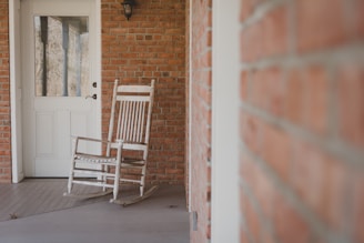 An antique rocking chair moving gently on a porch of a Victorian house, bathed in moonlight.