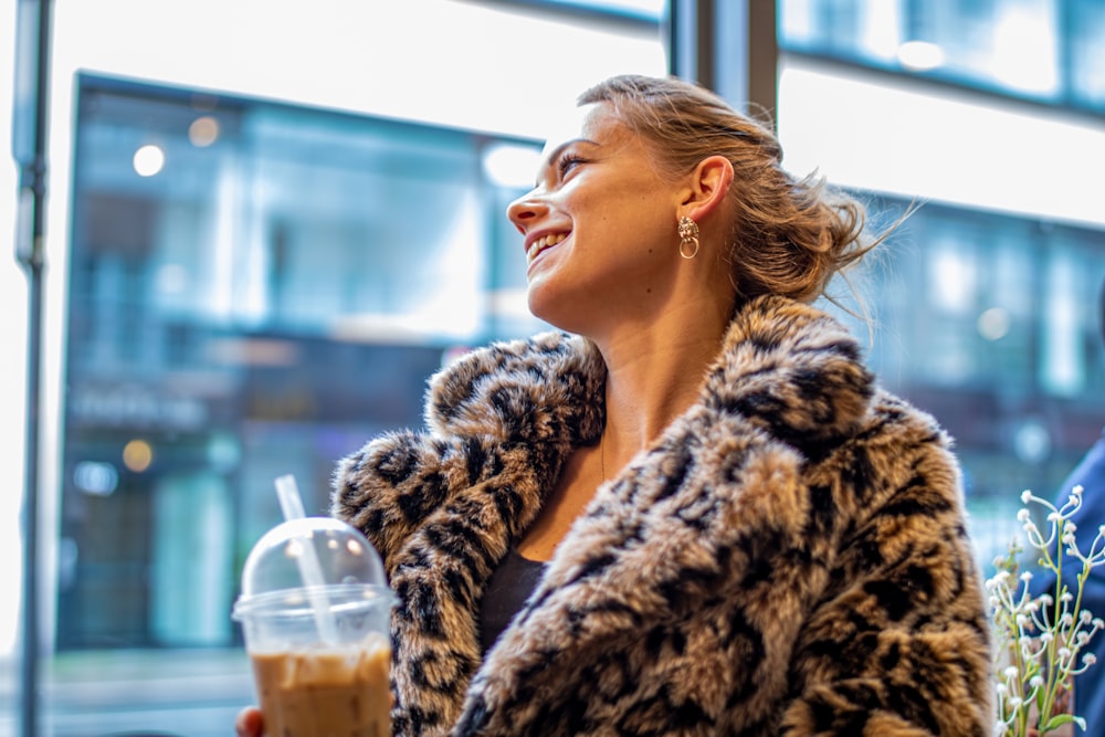 woman in brown coat holding cup