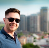 man wearing blue polo shirt with building background