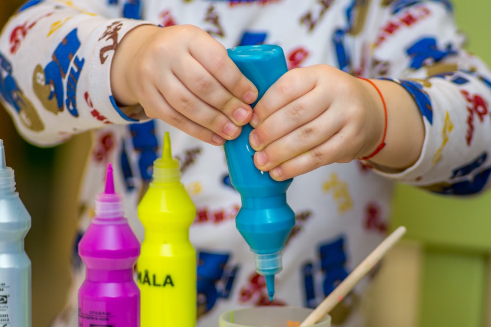 person squeezing bottle on a container