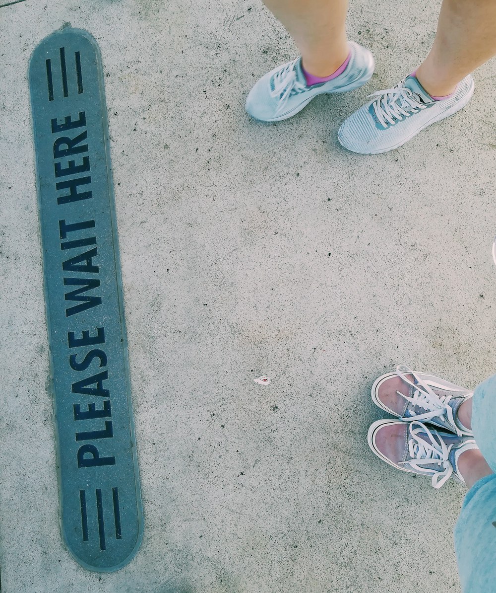 two person standing near the Please Wait Here signage