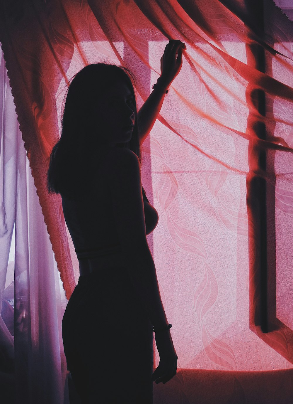 woman standing and holding red mesh curtain