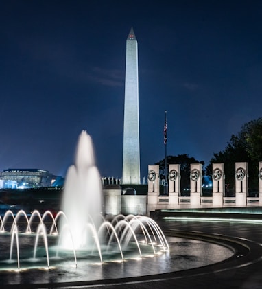 lighted tower building near water fountain in timelapse photo