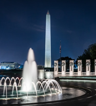 lighted tower building near water fountain in timelapse photo