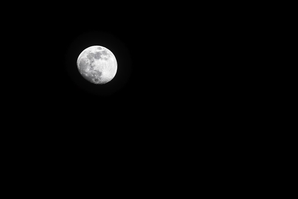 a full moon is seen in the dark sky