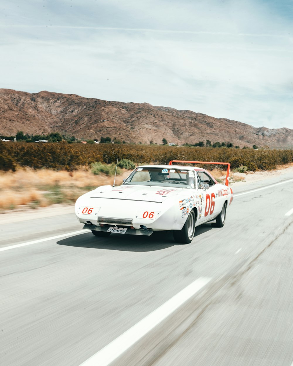 white coupe on road near grass