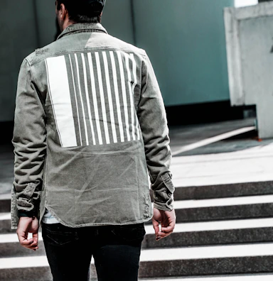 Model wearing the pine olive jacket standing against a minimalist urban backdrop.