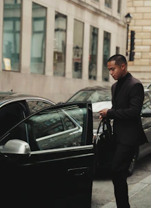 man in black tuxedo standing beside car