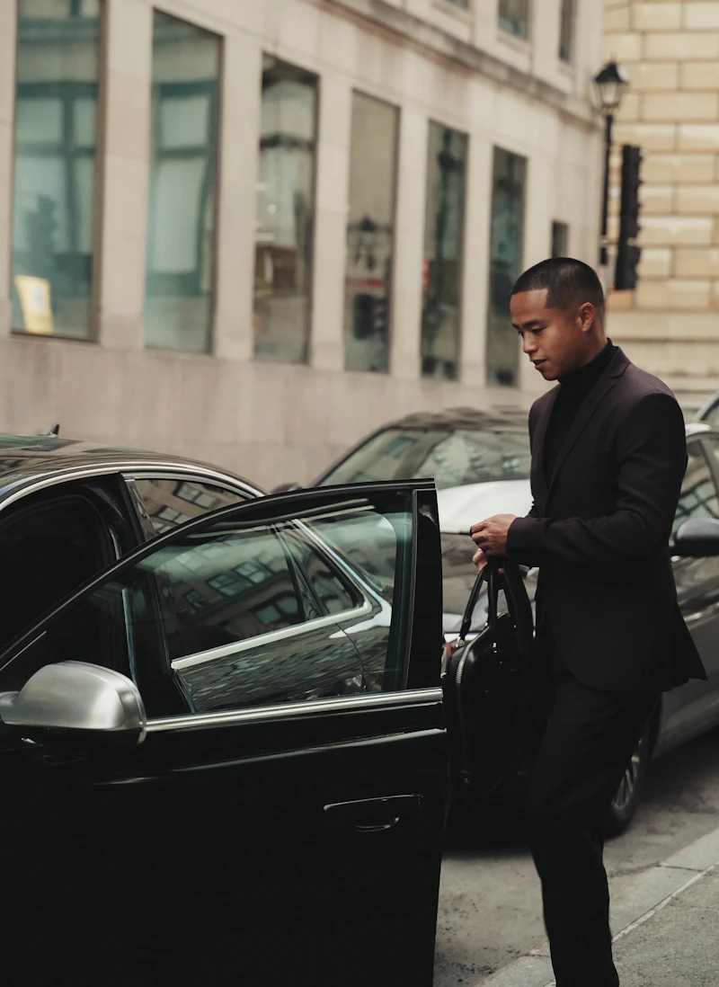 New Class Limo chauffeur in uniform beside a black luxury sedan, Houston