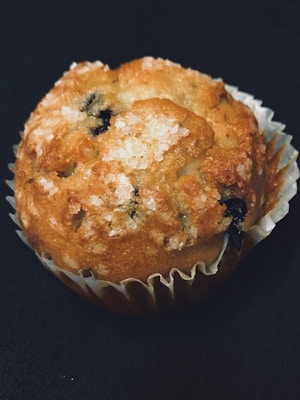 A vibrant photo of a fresh gluten-free berry muffin resting on a rustic wooden table.
