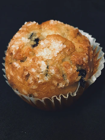 Close-up of a moist, fluffy high-protein muffin topped with blueberries and a light dusting of powdered sugar.