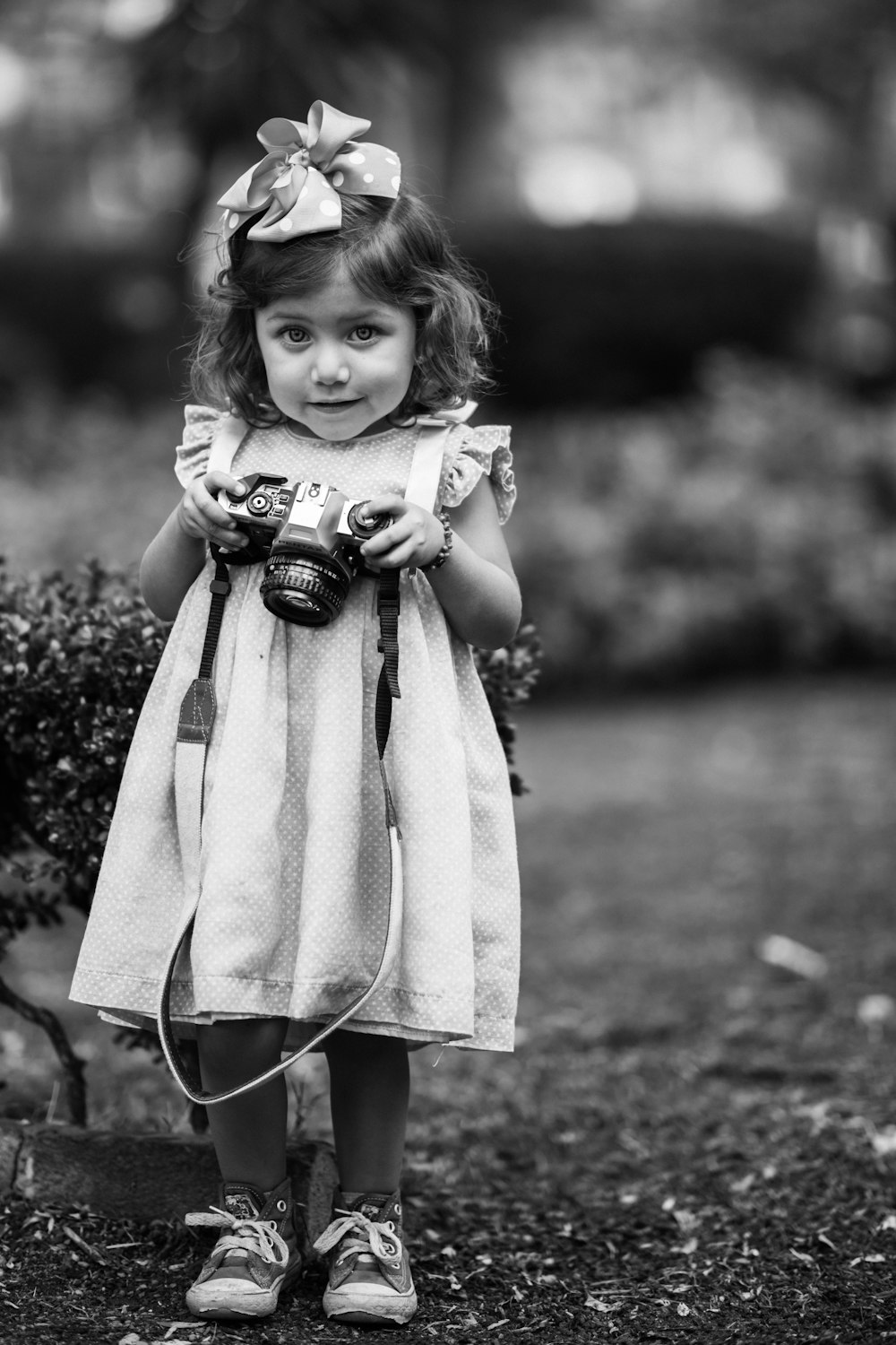 girl holding DSLR camera in grayscale photo