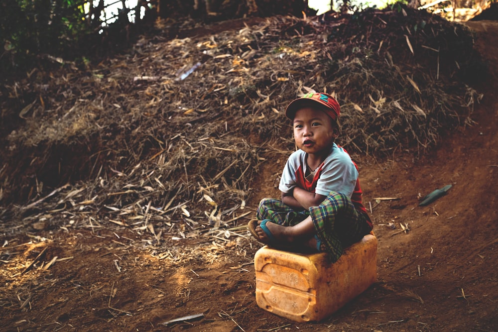 boy sitting on yellow container
