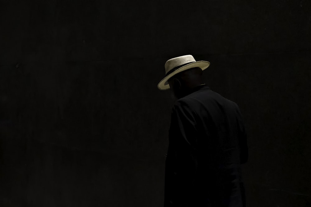 a man with a hat standing in the dark
